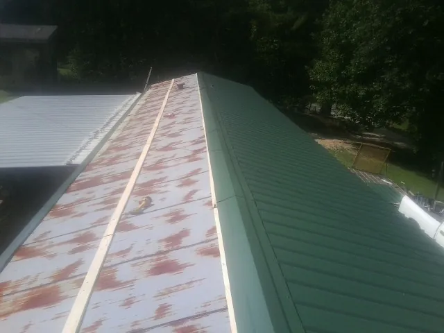 Old rusted panels beside newly installed green metal roofing — Wind Damage Roof Repair by Roofing Brothers in La Vista