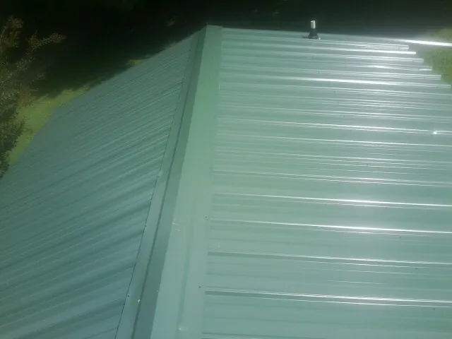 New green metal panels meeting at the ridge of a roof — Flat Roof Repair work by our crew in La Vista