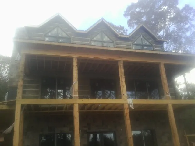 Dormers and porch framing on a large log home under construction — Roof Coating work by our crew in La Vista