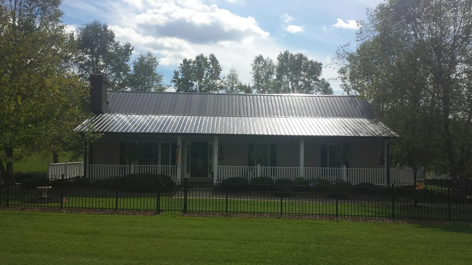 Gray metal roof on a brick ranch with a full width front porch — Gutter Guard Installation work by our crew in La Vista